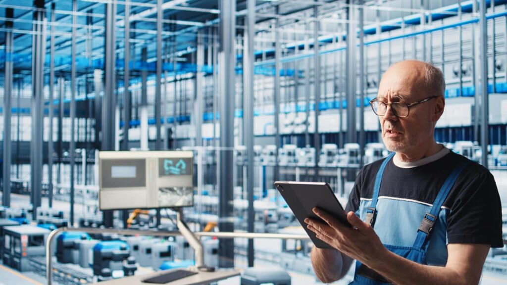 Ingénieur en usine utilisant une tablette pour surveiller et analyser les données de maintenance IoT