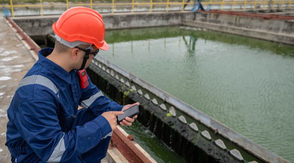 Des techniciens de maintenance et des ingénieurs mécaniques vérifient le système de contrôle d’une station de traitement de l’eau, entourés de pompes et de vannes.
