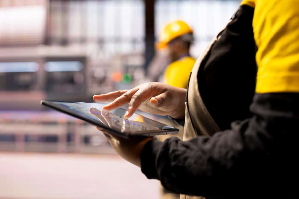 Technicien terrain consultant une intervention sur tablette mobile en environnement industriel