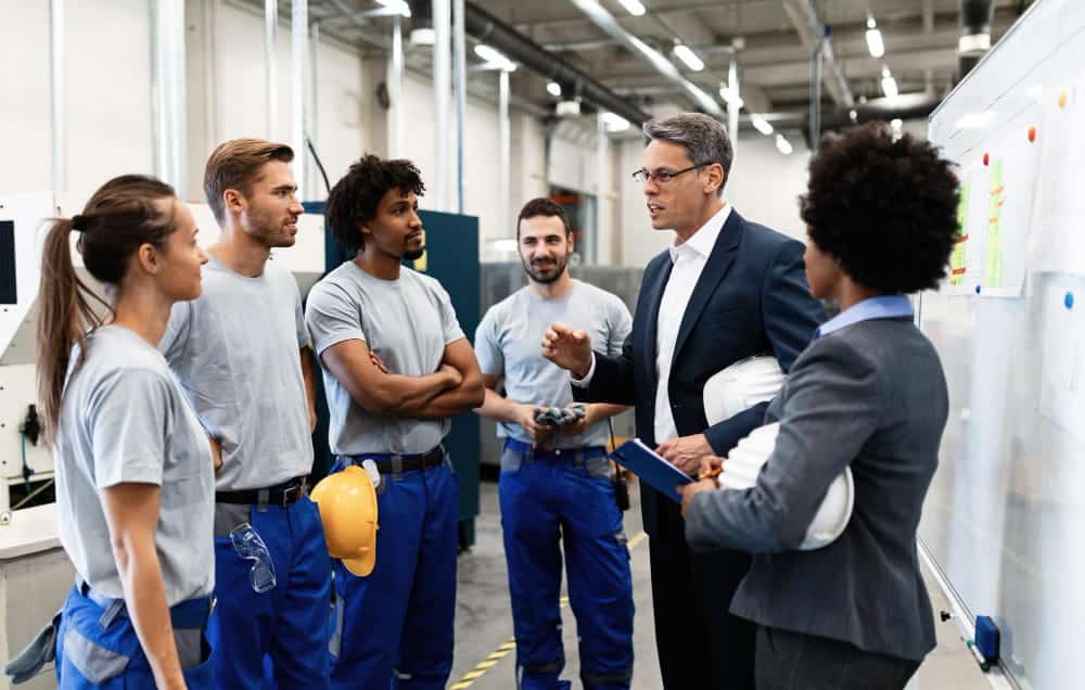 Responsable maintenance animant un briefing avec son équipe de techniciens en usine